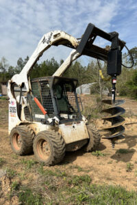 skid steerer digging hole for fence posts